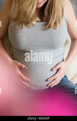 Kaukasische werdende Mutter Bauch Holding Stockfoto