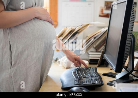 Kaukasische werdende Mutter mit Computer Stockfoto