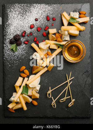 Käse und Nüsse mit Honig auf Schiefer Stockfoto