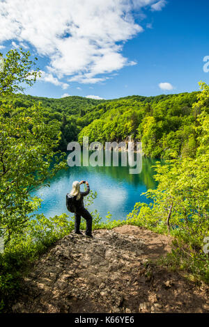 Ältere kaukasische Frau fotografieren Wasserfall mit Handy Stockfoto
