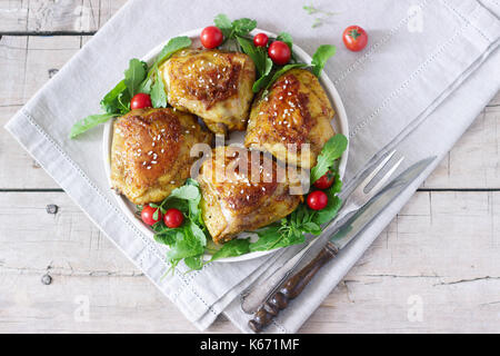 Gebackene Hühnerkeule mit Garnierung von Rucola und Tomaten. Rustikaler Stil, selektiven Fokus. Stockfoto
