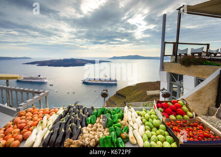 Blick am Abend von Fira, Caldera, Vulkan von Santorini, Griechenland mit Kreuzfahrtschiffen bei Sonnenuntergang. Dramatischer Wolkenhimmel. Stockfoto