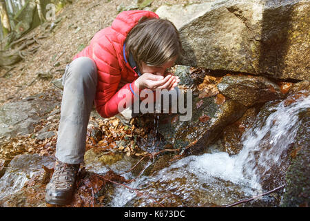 Durstigen Wanderer Trinkwasser aus einer kristallklaren Bach in den Bergen. Abenteuer, Grundrecht auf Wasser, zurück zur Natur und natürliche Lebensweise Stockfoto