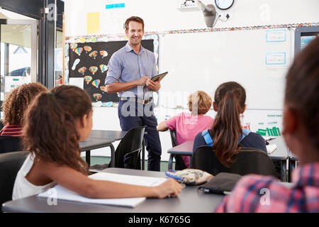 Lehrer mit Tablette vor der Grundschule Klasse Stockfoto