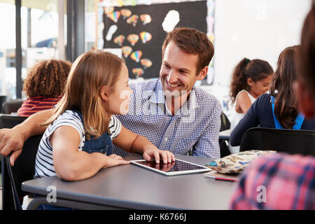 Lehrerin und Schülerin mit Tablet sich einander Stockfoto