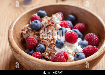 Ricotta Frischkäse zum Frühstück mit Müsli, Honig und Beeren Himbeeren Blaubeeren Stockfoto