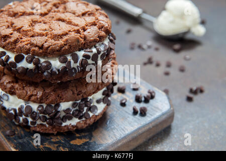 Hausgemachtes Vanilleeis Sandwiches mit Schokolade tropfen Cookies auf dunklem Hintergrund Stockfoto