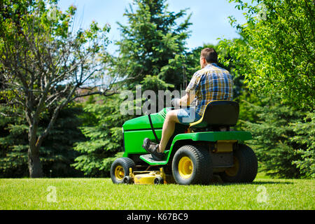 Man mähen den Rasen auf einem Sitzen Mäher Stockfoto