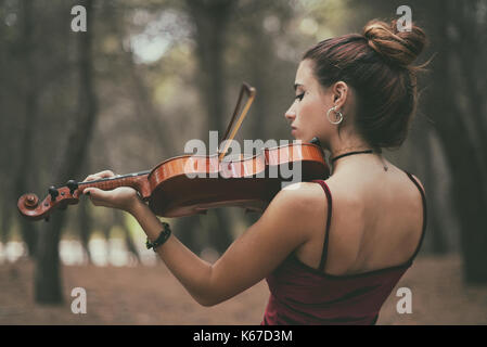 Stehendes Mädchen im Wald spielen der Violine Stockfoto