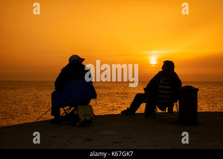 Zwei alte Männer Fischen bei Sonnenuntergang im Hafen von Tapia de Casariego. Asturien. Spanien. Stockfoto