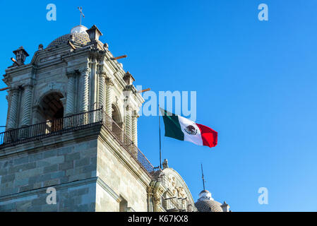 Mexikanische Flagge über Unsere Liebe Frau Mariä Himmelfahrt Kirche in Oaxaca, Mexiko am 4. März 2017 fliegen Stockfoto