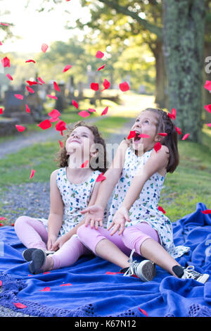 Zwei kleine Mädchen kreischen oder quietschen vor Vergnügen wie Blumen und auf sie geworfen Stockfoto