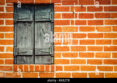 Eine Rote Backsteinmauer und abgenutzte hölzerne Fensterläden in einem alten San Diego Gegend. Stockfoto