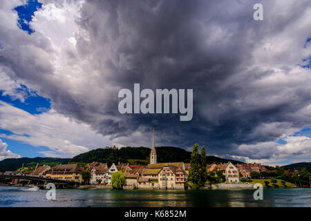 Ein Blick auf die kleine Stadt über den Rhein, dunkle Gewitterwolken über Stockfoto