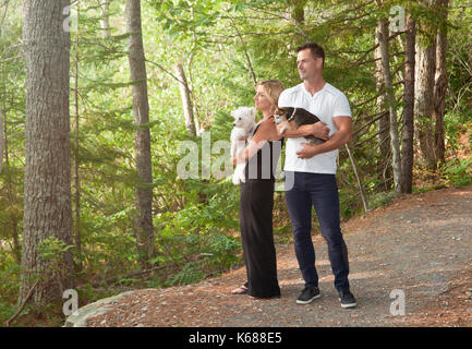 Ein Mann und eine Frau mit ihrem kleinen Hunde stehen auf einem Waldweg, mit Blick auf den Wald Stockfoto