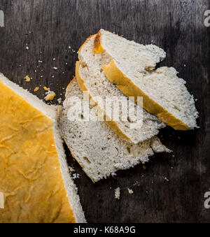 Home gemacht Brot, drei Scheiben geschnitten, oben auf einem dunklen Holz- Oberfläche Stockfoto