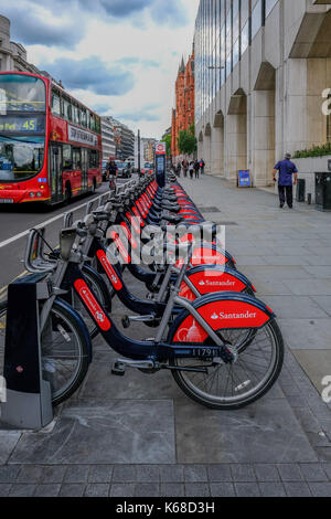 London, Großbritannien, 31. Mai 2017, Reihe von Santander Zyklen bereit für Mietwagen in High Holborn. mit Bus und Taxi vorbei auf der Straße. Stockfoto