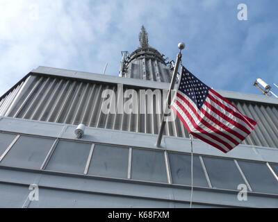 Flagge auf der Spitze des Empire State Building in New York City entfaltet. Stockfoto