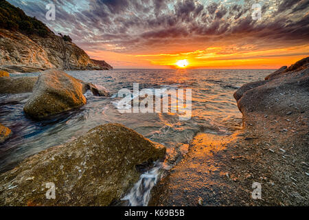 Malerischer Sonnenuntergang an der Küste mit orangefarbenem Licht in der Bucht von Saint Andrew auf der Insel Elba Stockfoto