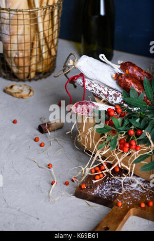 Salami mit frischem Brot und Wein. Verschiedene Sorten Salami und hart geräucherte Würstchen. Antipasti Zutaten. Stockfoto