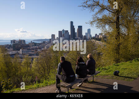 Menschen entspannend auf einer Bank in der Innenstadt von Seattle City Skyline im Hintergrund. Bild in Dr. Jose Rizal Park, Washington, USA. Stockfoto