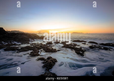 Schönen winter Sonnenaufgang am felsigen Pacific Ocean Shore. Bild in Amphitrite Point Lighthouse, Ucluelet, Vancouver Island, British Columbia, Stockfoto