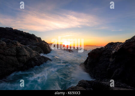 Schönen winter Sonnenaufgang am felsigen Pacific Ocean Shore. Bild in Amphitrite Point Lighthouse, Ucluelet, Vancouver Island, British Columbia, Stockfoto