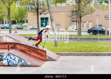 Saguenay, Kanada - Juni 3, 2017: Downtown City Sommer Park in Quebec mit junger Teenager boy Skaten, Tricks, Stunts auf Roller, Reiten auf Stockfoto