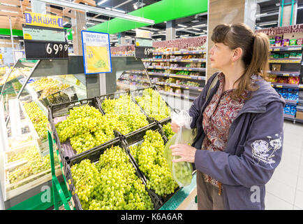 Samara, Russland - September 5, 2017: Junge Frau Auswahl von frischen Weintrauben bei Einkaufen im Supermarkt Stockfoto