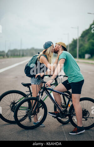 Romantische Sport paar Küssen gegen verschwommenen Hintergrund mit Fahrrädern. Rosa Kinesio tape auf der Hand des Mädchens geklebt. Close-up Stockfoto