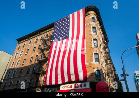 Riesige amerikanische Flagge aufhängen auf einem Mietshaus in Chinatown, New York City, in Lower Manhattan. Stockfoto