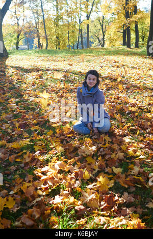 Glückliche junge jugendlich Mädchen im Herbst Landschaft werfen Blätter Stockfoto