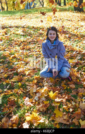 Glückliche junge jugendlich Mädchen im Herbst Landschaft werfen Blätter Stockfoto