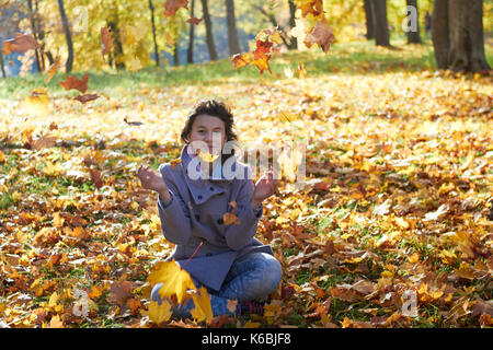 Glückliche junge jugendlich Mädchen im Herbst Landschaft werfen Blätter Stockfoto