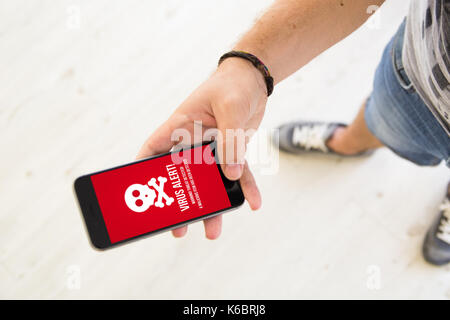 Nahaufnahme der männlichen Hand mit Smartphone Virus Alarm Stockfoto