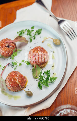 Beef Tartar mit einem Ei auf einer Steinplatte. Cherry Tomaten. Rosmarin. Gewürz. Stockfoto