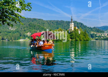 Touristen auf einem Boot aus Bled Insel, blejski otok, mit der Wallfahrtskirche zu Maria Himmelfahrt über See gesehen dedizierte Bled, blejsk Stockfoto