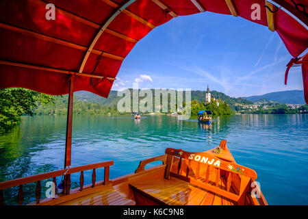 Touristen auf einem Boot aus Bled Insel, blejski otok, mit der Wallfahrtskirche zu Maria Himmelfahrt über See gesehen dedizierte Bled, blejsk Stockfoto