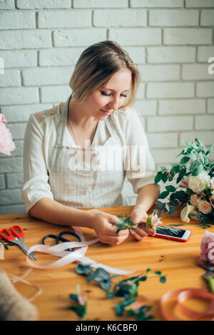 Schöne junge Frau Floristen arrangieren Pflanzen im Blumenladen lächelnd Stockfoto