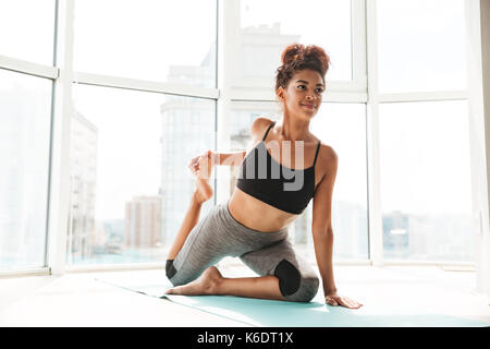 Afrikanische Frau schwierige Yoga Übung auf dem Boden zu Hause konzentriert Stockfoto