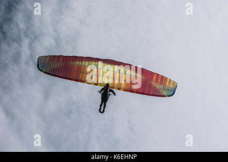 Gleitschirm fliegen gegen den Himmel mit weißen Wolken. Fallschirm auf einem klaren blauen sonnigen Tag mit Sonne und Wolken. Stockfoto