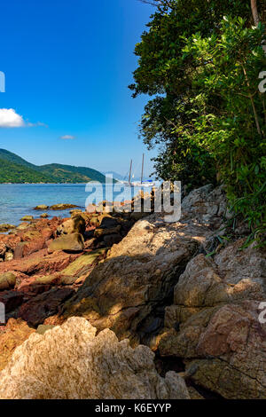 Segelboot an Suny und klarer Sicht über das Meer und zwischen Inseln und Wald Stockfoto