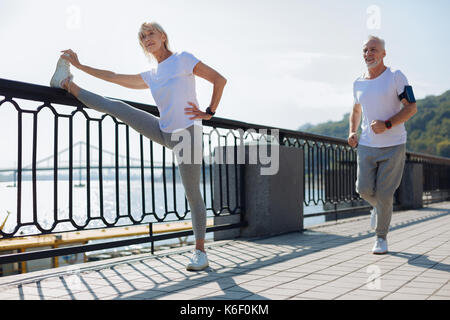Passende Frau zu tun Stretching während man Joggen Stockfoto