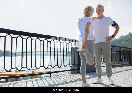 Passen älterer Mann seine Frau helfen Sie Dehnübungen Stockfoto