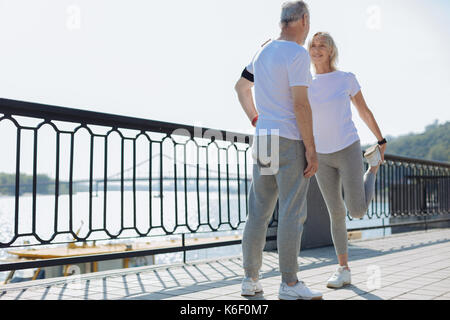 Fröhliche Frau Stretching und lehnte sich auf Ehemänner Schulter Stockfoto