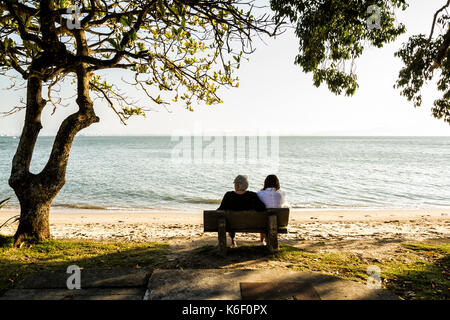 Mutter und Tochter sitzen auf einer Bank am Strand von Santo Antonio de Lisboa. Florianopolis, Santa Catarina, Brasilien. Stockfoto