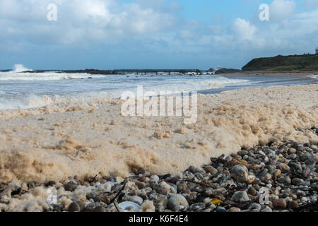 Bewölktem Himmel, wilde Küstenlandschaft und das Meer Schaum oder Gischt, Waschen der Kiesstrand in Carrickmore Rd, BT54, Ballycastle, Nordirland, Großbritannien Stockfoto