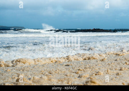 Bewölktem Himmel, wilde Küstenlandschaft und das Meer Schaum oder Gischt, Waschen der Kiesstrand in Carrickmore Rd, BT54, Ballycastle, Nordirland, Großbritannien Stockfoto