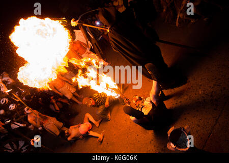 Eine junge Salvadorianische Mann, auf dem Rücken liegend, spuckt Feuer, wie er während des La Calabiuza Parade am Tag der Toten Feier in Tonacatepequ Stockfoto