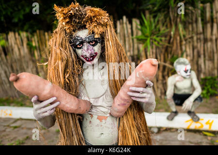 Eine junge Salvadorianische Mann, malte eine Aschgraue grau und das Tragen einer Maske, führt eine indigenen Mythologie Charakter in der La Calabiuza Parade am Tag der Stockfoto